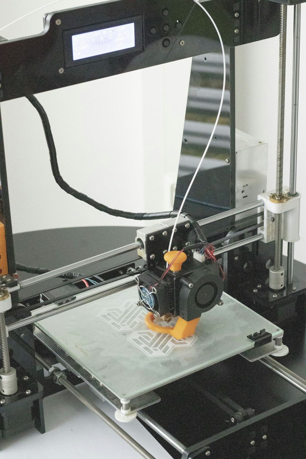 Imprimante 3D en train de fabriquer une pièce orange